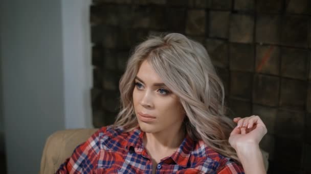 Close-up of face and belly of pretty young pregnant woman in plaid shirt and blue jeans who is sitting in the armchair, thinking and touching her tummy lovingly. Young married woman relaxing in the — Stock Video