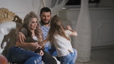 Baba, anne ve küçük kızı mutlu aile bebek bekliyor vardır. Üç mutlu insanlar birlikte birbirlerine sarılma ve gülümseyen kanepede oturuyor.