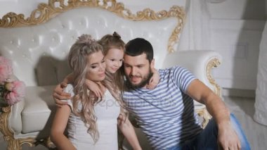 Birlikte oturan ve sarılma mutlu aile bekliyor yeni bebek. Hamile anne ve babasıyla birlikte kanepede yakın katta oturuyor. Küçük kız kanepede yatıyor