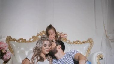 Birlikte halı üzerinde oturan ve sarılma mutlu aile bekliyor yeni bebek. Hamile anne ve babasıyla birlikte kanepede yakın katta oturuyor. Karısı ve kızı öpüşme baba.