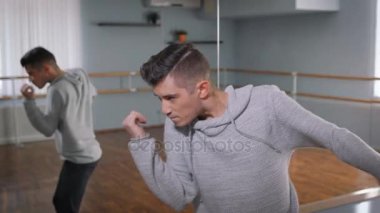 Genç dansçı gri kazak ve siyah pantolon ayna dans kapatın. Dans okulu, genç öğrenci sınava hazırlanıyor ve modern dans ayna yakınındaki tutkuyla gerçekleştirme.