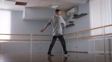 Gri kazak ve siyah pantolon sınıf ortasında dans yakışıklı erkek dansçı. Dans okulu öğrencisi genç modern dans tutkusu ile unsurları eğitim.