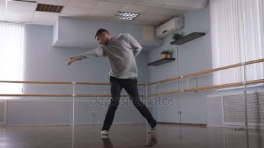 Genç güzel dans dans stüdyosunda hamle yapan adam. Bir gri kazak ve siyah pantolon giyen dansçı danslarının gösteriden önce prova.