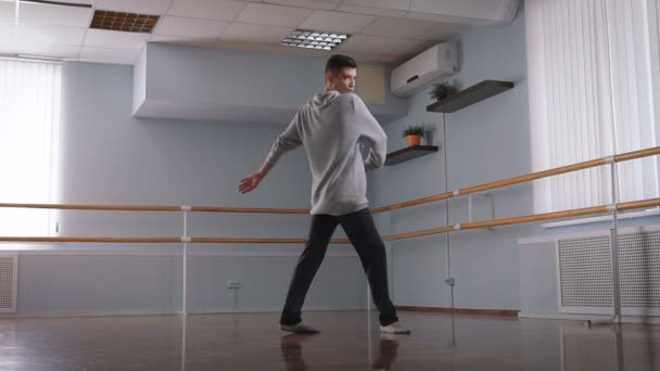 Stilig manliga dansare i grå tröja och svarta byxor Dans i mitten av klassrummet. Ung student på dansskola är utbildning element av modern dans med passion. — Stockvideo