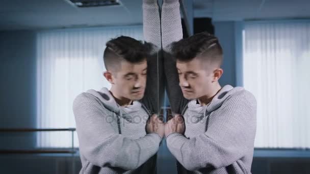 Gutaussehender Typ tanzt emotionalen Tanz, der neben dem Spiegel im Tanzstudio steht. Probe des modernen Tanzes. — Stockvideo