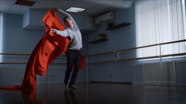 Professional dancer finishes his dance of beautiful wave of red cloth in front of him. Guy picks up a big red cloth and then puts it on the floor. Modern dance. — Stock Video