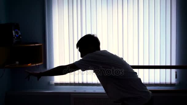 Silhouette man against the window, which is dancing hip-hop in the dance studio. Performance of young dancer in a low-light dance hall. — Stock Video