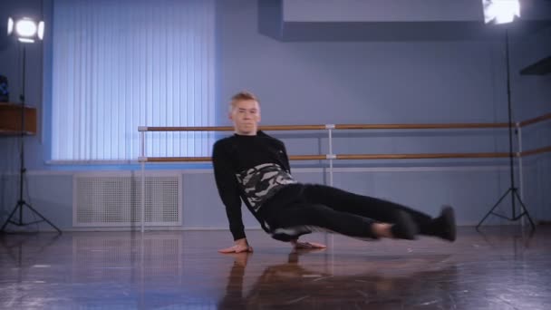 プロのブレイク ダンサーは、ダンス スタジオの床の上の彼の壮大なダンスを踊る。よく訓練されたダンスの動き。若い男の子は手の上に立ってそれ自身を保持します。. — ストック動画