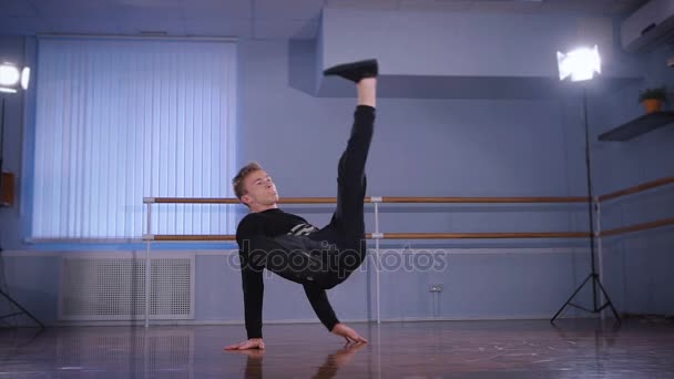 Bailarín profesional realiza movimientos de baile irrealistas y pesados en el suelo en un estudio de baile. Fuerte joven comprometido en breakdance . — Vídeo de stock