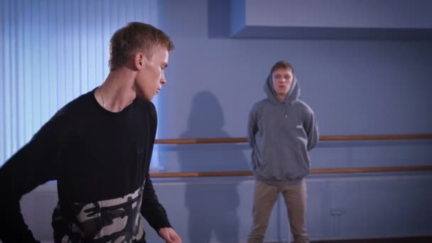 Hall för repetitioner danser. Två unga dansare. Den unga killen i en svart jacka fungerar förehavanden av lägre avbrottet. Och oponnt honom att dansa team ser på honom. — Stockvideo