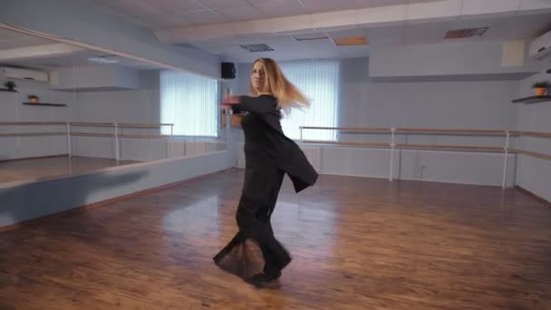 Una mujer en un estudio vacío toma clases de baile. Este es su hobby. Ensaya de buen humor. Intenta hacer una rotación de 360 grados. Muchas personas involucradas en la danza por placer . — Vídeos de Stock