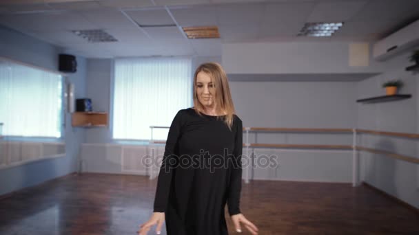 Nahaufnahme der schönen weißhaarigen Frau im seidenschwarzen Anzug, die das Tanzen als ihr Hobby betrachtet und im Klassenzimmer mit Ballettbarre und Spiegel an den Wänden trainiert. — Stockvideo