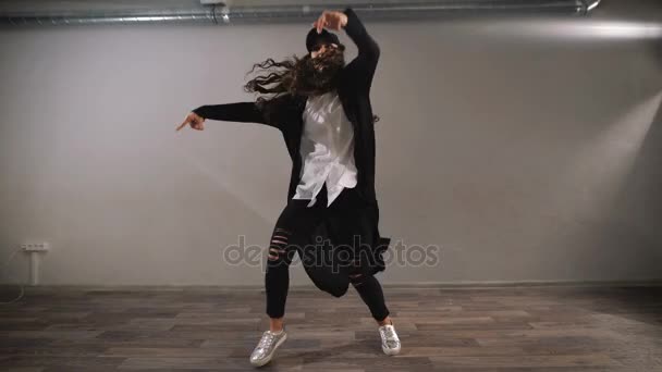 Bailarina de camisa blanca, pantalón negro y gorra negra que muestra el jazz-funk moderno bailando en clase con espejos. Chica bailando y profesionalmente haciendo elementos de danza urbana . — Vídeos de Stock