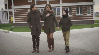 Gri ceket, eşi ve çocuk cortyard adam. Evinin bahçesinde gidiyorlar. Aile yürüyüş, aşk, mutlu bir aile güneşli havalarda kişileştirme.