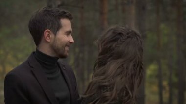 Sonbahar parkta birlikte vakit genç mutlu çiftin yakın çekim. Erkek ve kadın arasında ağaçlar ayakta, birbirine bakarak gülen.