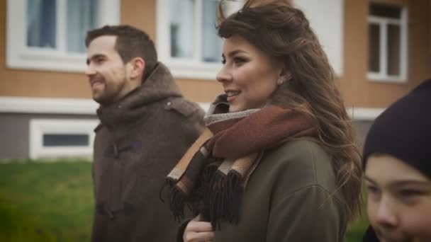 Primo piano di padre, madre e figlio felici che fanno una passeggiata insieme. Padre e figlio stanno sorridendo. La mamma sta camminando lungo il sentiero tenendo la mano sul petto e raccontando qualcosa alla sua famiglia. . — Video Stock