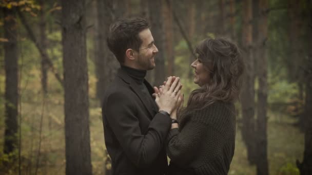 Feliz esposa y esposo pasando el fin de semana en el bosque. Sonriendo hombre y mujer de pie en el bosque con un montón de árboles detrás, mirándose unos a otros y riendo feliz . — Vídeos de Stock