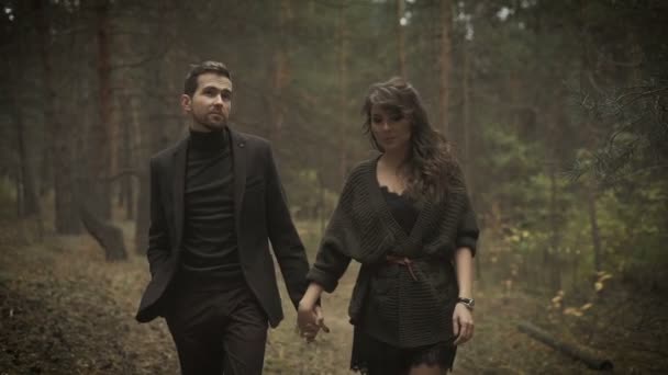 Close up of happy man and woman together walking on the path in the forest. Smiling couple are strolling among the forest, keeping their hands together and laughing happy. — Stock Video