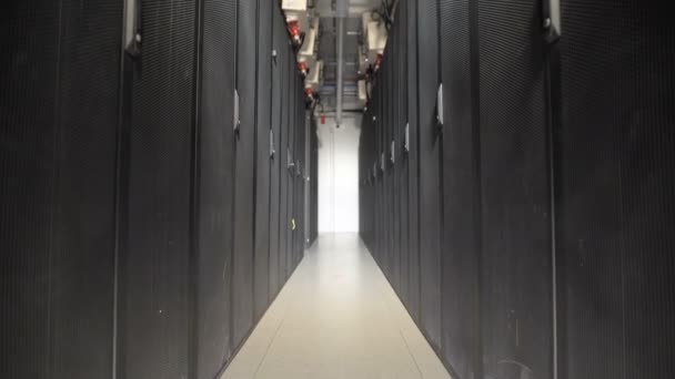 A long series of special cabinets designed for ventilation server on a large industrial plant. Devices connected to a common power supply by cables with red plug. Thin corridor with lamp for lighting. — Stock Video