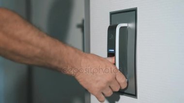 Adam kapıyı girmek için tasarlanmış bir parmak izi tarayıcı parmağını koyar. Modern güvenlik teknoloji çalışanların günlük hayatımızda. Hırsızlık karşı koruma çalışmalarını yakın çekim.