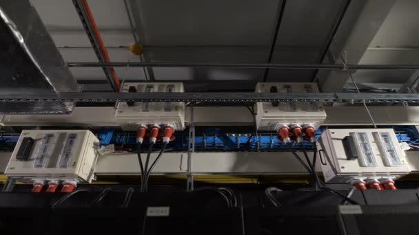 Several electric power units are equipped with a switch inside, attached under the ceiling in the industrial premises of IT companies. Devices connected to a common supply by cables with red plug. — Stock Video