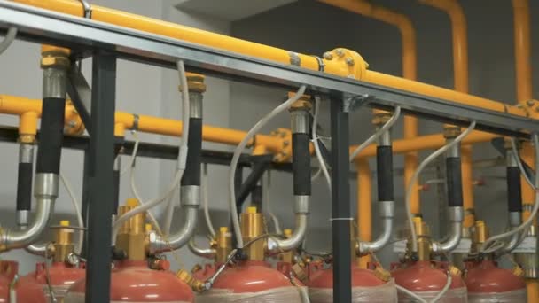 Eine große Anzahl von Gasflaschen ist mit einer einzigen Pipeline verbunden, die das Unternehmen mit Treibstoff versorgt. Gelbe und Chromrohre werden verwendet, um Geräte miteinander zu verbinden. — Stockvideo