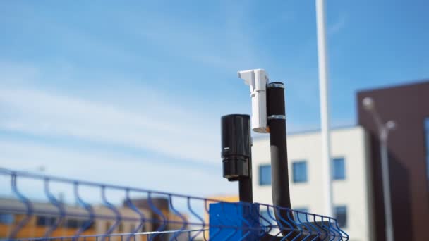 System of video surveillance and motion sensors are located on the corner of the fence. Modern equipment for the protection of the territory from outsiders. Several buildings on the background. — Stock Video