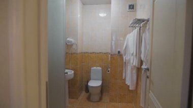 Banyo lavabo, tuvalet, ayna ve beyaz havlu ve bornoz bir askı üzerinde asılı. Oda hangi tazelemek için gereken her şeyi yoktur.
