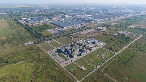 Estudio aéreo de una ciudad industrial. Muchos espacios verdes cerca de los edificios de la fábrica. Quadcopters filmando vídeo, acercándose a la ciudad . — Vídeo de stock