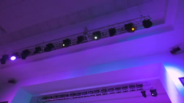 Концертне освітлювальне обладнання в роботі. Професійні проектори освітлення автоматично обертаються і сяють різних кольорів. Промені від світлового обладнання потрапляють в об'єктив камери . — стокове відео