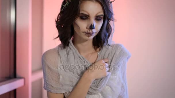 Närbild av en kropp ung flicka i vit brudklänning och hennes kreativa läskigt creepy halloween gör. med utseende sitter på bänken nära fönstret blomman i händer knän. — Stockvideo