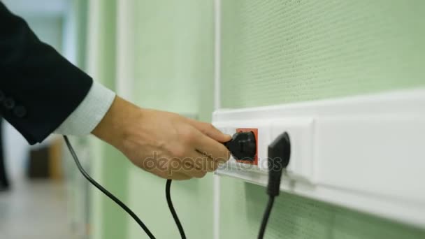 Close up of man hand putting plug in electricity socket to charge the laptop. — Stock Video