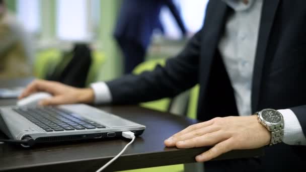 Close-up de mãos masculinas com bom relógio enquanto trabalhava no laptop digitando algo no teclado e usando o mouse. Jovem empresário está preparando o projeto para trazê-lo para o público com colegas — Vídeo de Stock