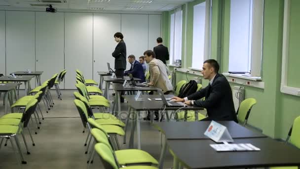 La audiencia para los seminarios en la universidad. Seminario de formación para estudiantes. Hombre en su escritorio trabajando en un ordenador portátil, está preparando un programa para el taller . — Vídeos de Stock