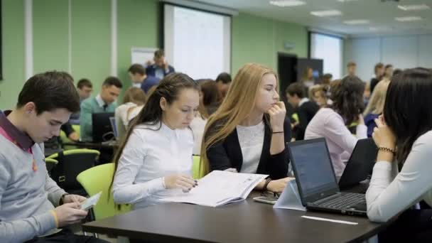 Skupina mladých podnikatelů za stolem se účastní soutěživé učení s start-up projekty. Tým čtyř lidí je připraven a čeká na řadě mluvit. — Stock video