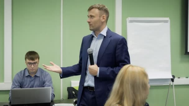 High school-lärare föreläser om ekonomi i university klassrummet. Det är med hjälp av bilder och grafer på skärmen förklarar för eleverna grunderna i ekonomin. — Stockvideo