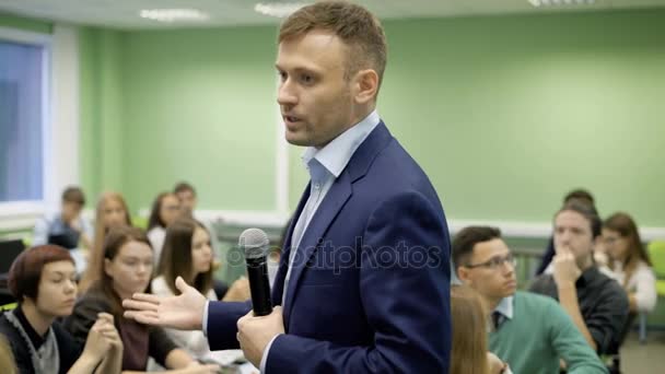 Carismático joven entrenador de negocios con micrófono hace un informe delante de una audiencia en el negocio Desayuno . — Vídeos de Stock