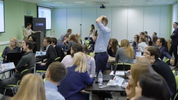 Un experimentado entrenador de negocios, hablando en una conferencia frente a un gran número de gerentes. El hombre muestra la imagen del proyector y la comenta. Amplias salas modernas para conferencias . — Vídeos de Stock