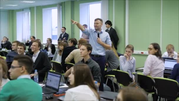 Young business trainer with a microphone shows up on the projector screen while waiting for the final results. — Stock Video