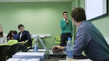 Projeksiyon ekranında ayakta ve konuşan genç zeki öğrenci.