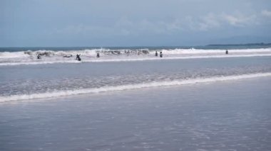 Çok sayıda sörfçü bir dalga kıyıları yakalamaya çalışıyor. İnsanlar tatilde ve denize sadece yüzme sörf.