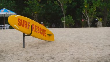 Parlak sarı ve kırmızı sörf tahtası üzerinde Bali kumlu plaj adanın yalan söylüyor. Sörf için multicolour kurulu bir Endonezya plajlar yalnız kum üzerinde duruyor.
