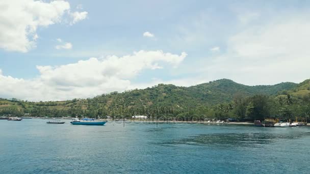 Несколько небольших лодок пришвартовались рядом с красивым тропическим островом. Большой залив с чистой голубой водой в океане. Причал для яхт, моторных лодок и парусников у берега . — стоковое видео