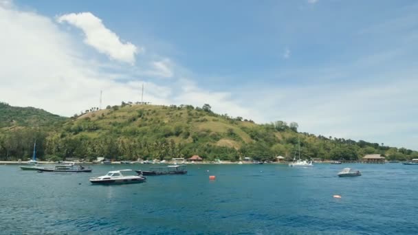 Wonderful scene of island in the sea with jetty and yachts along the seashore. Balinese landscape of blue sky and turquoise water. Indonesian breathtaking colours of the ocean and sky. — Stock Video