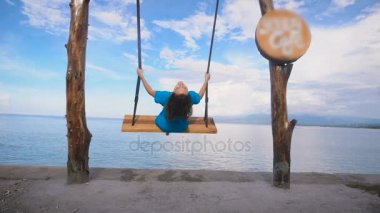 Okyanus Bali Beach. Kız. Salıncak. Turkuaz Okyanusu, açık gökyüzü. Bir salıncak üzerinde mavi elbiseli kız. Bu konumdan unutulmaz, Bali Adası manzaralıdır