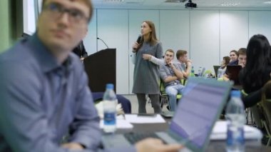 Kız öğrenci bir mikrofon ve projektör kullanarak Üniversitesi'nde bir seminerde konuşuyor. Modern ders saatidir. Adam gözlük ve bir dizüstü bilgisayar