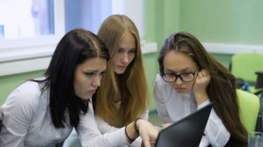 Üç iş kadın beyaz bluz doğru kararı bulmak için dizüstü bilgisayar kullanma.