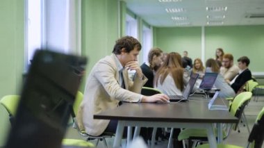 Modern üniversitelerinin eğitim sürecinde. Öğrencilerin gruplar halinde masalarda oturan ve dizüstü bilgisayar ekranı ile malzeme ders öğrenin. Geniş ve ferah sınıf.