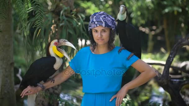 La fille dans le parc d'oiseaux et de reptiles sur l'île de Bali. Elle est d'excellente humeur est photographiée avec des oiseaux. Ptitsy-nosorgi à ses épaules . — Video