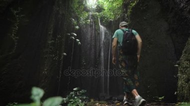 Genç adam bir kap ve bir sırt çantası içinde inanılmaz güzel bir şelale orman ulaştı. El değmemiş doğa güzelliği zevk turizm.